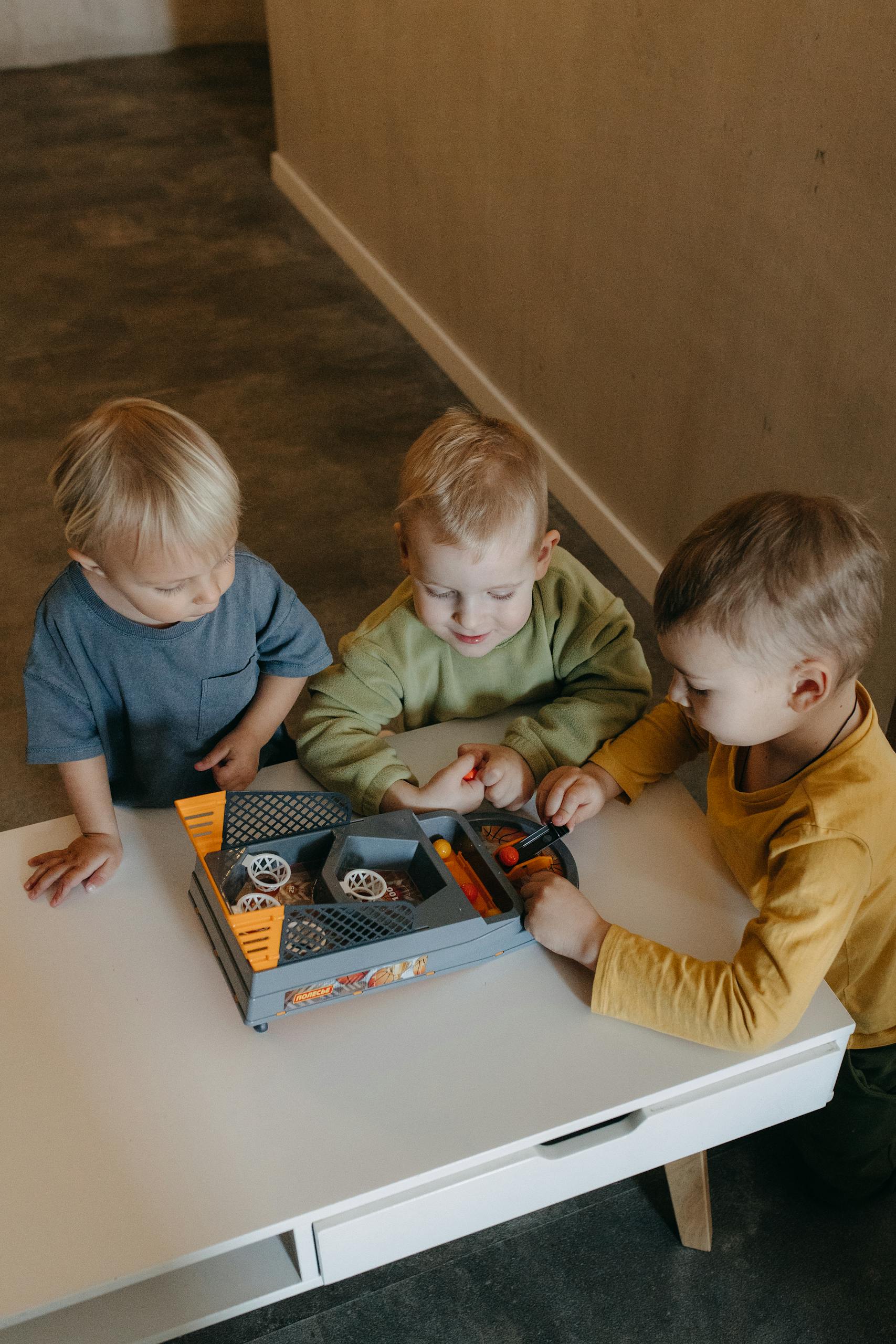 Three children playing with a toy car on a table