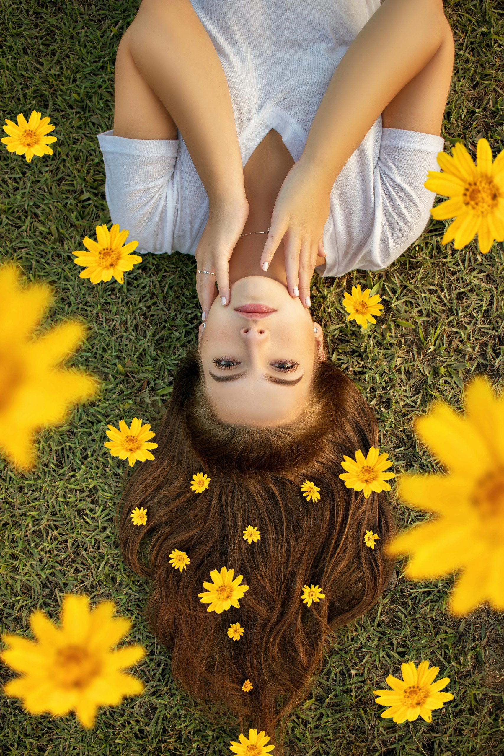 Seasonal Hair Care Tips: Upside down portrait of a woman lying on grass with yellow flowers in her hair.